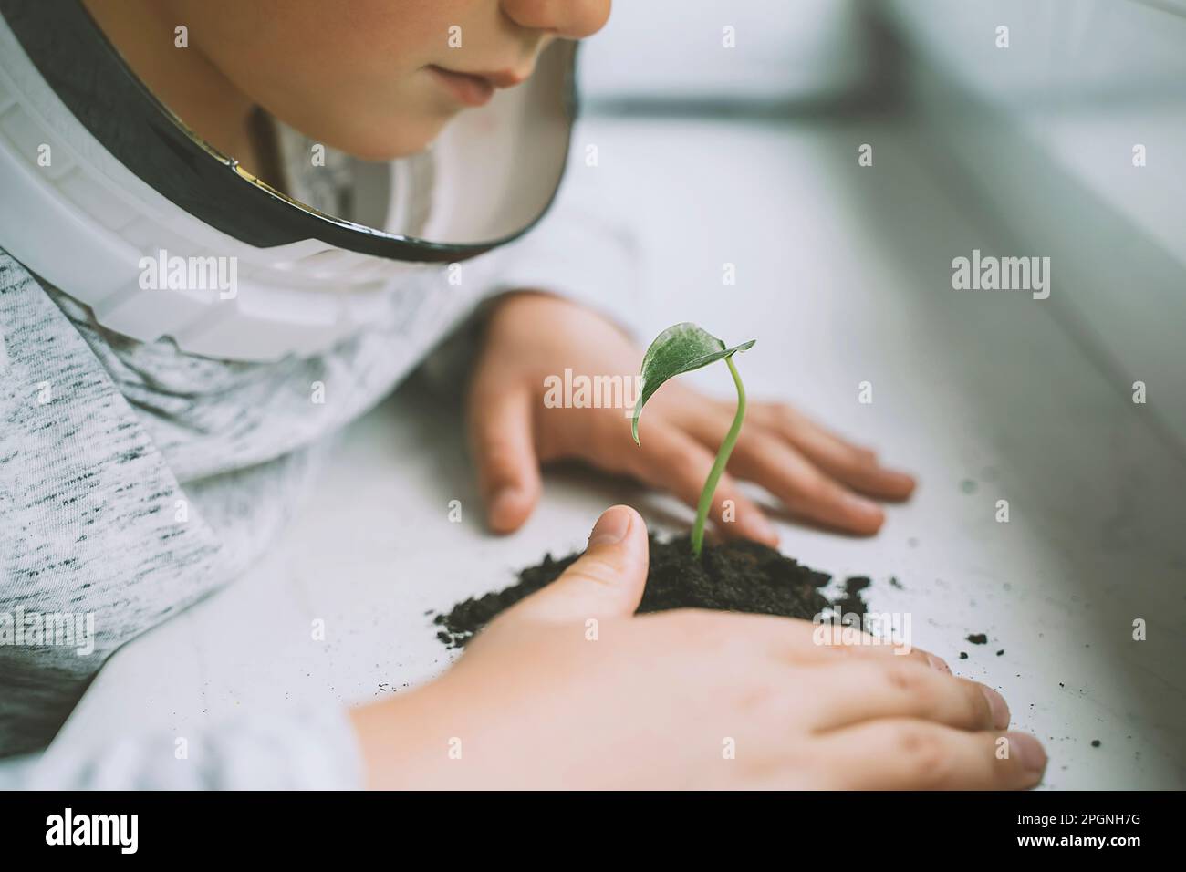 Ragazzo che indossa il casco spaziale guardando la pianta Foto Stock