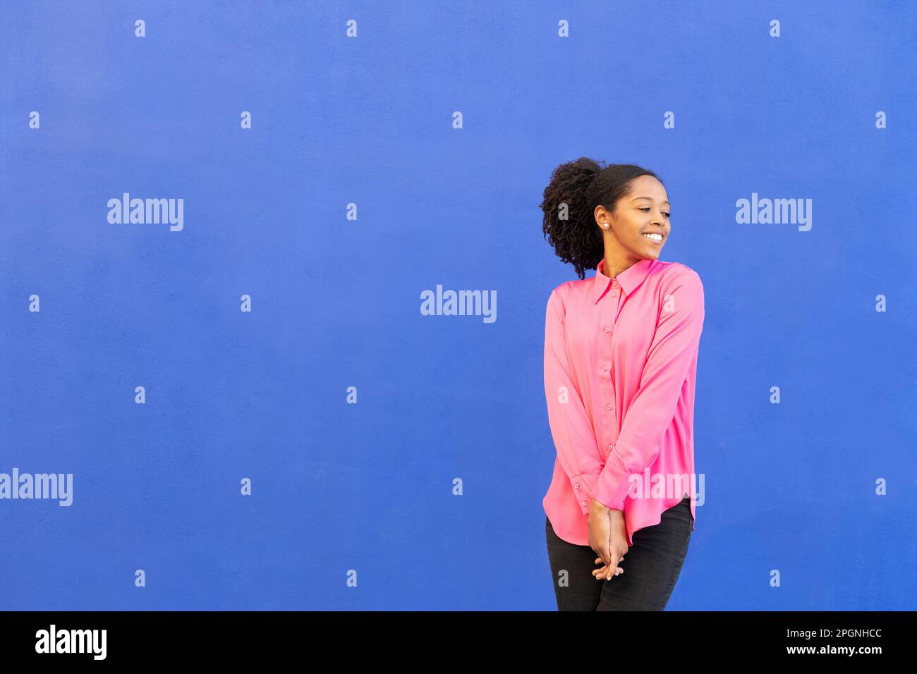Donna felice che indossa una camicia rosa di fronte alla parete blu Foto Stock