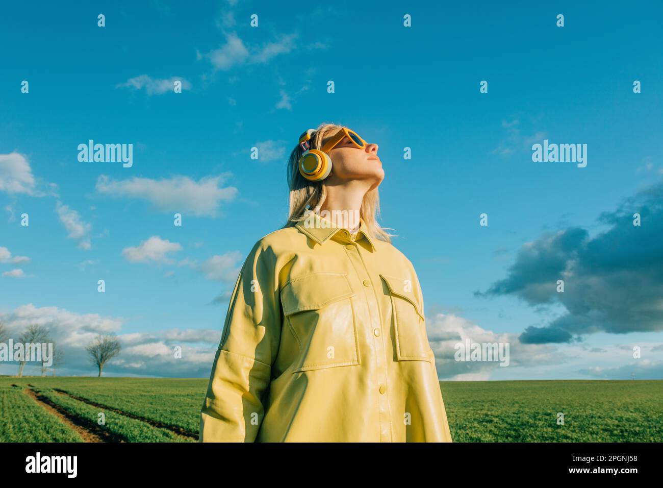Donna che indossa una camicia gialla sotto il cielo blu Foto Stock