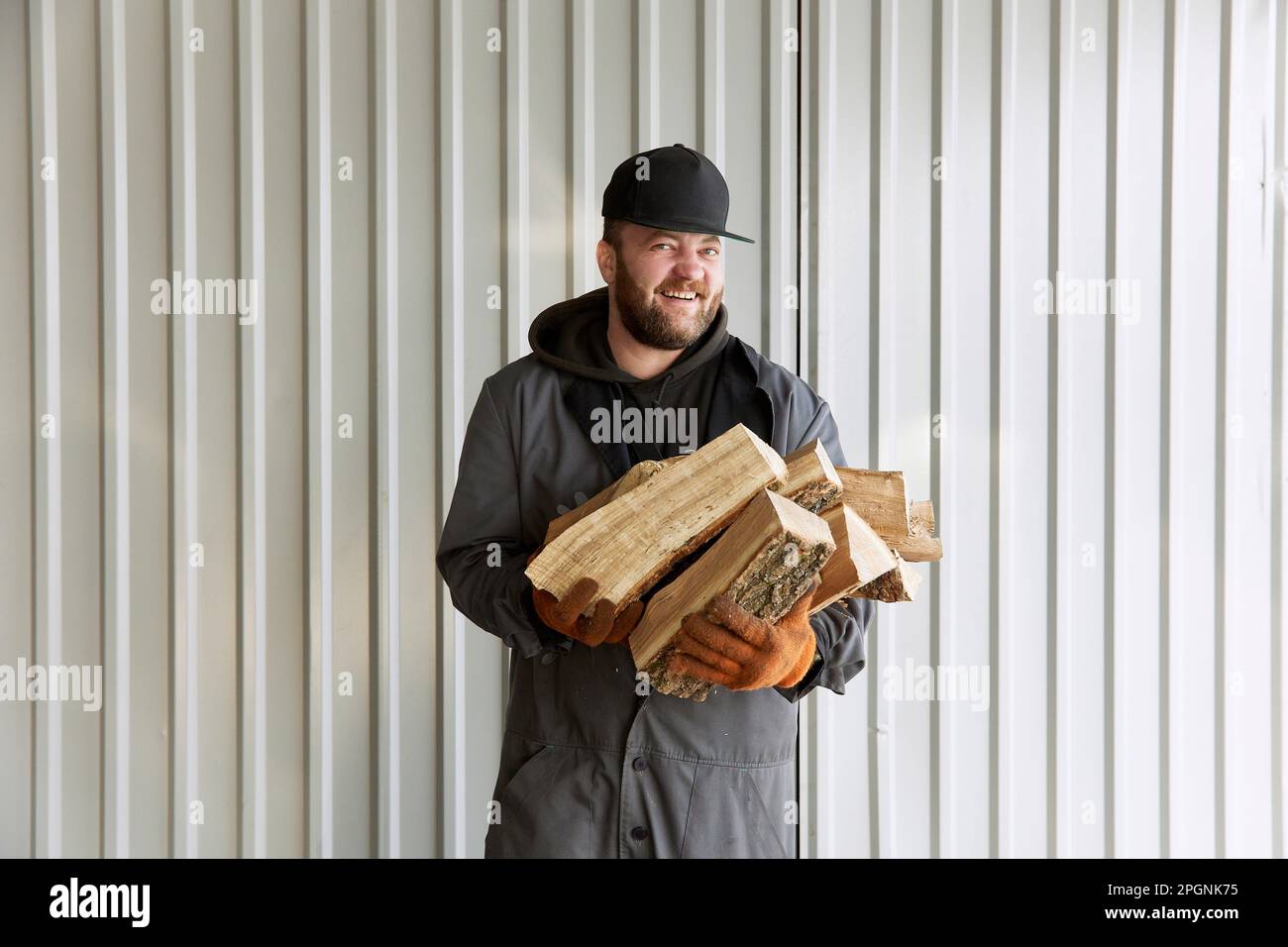 Chef felice con legna da ardere in piedi di fronte al muro Foto Stock