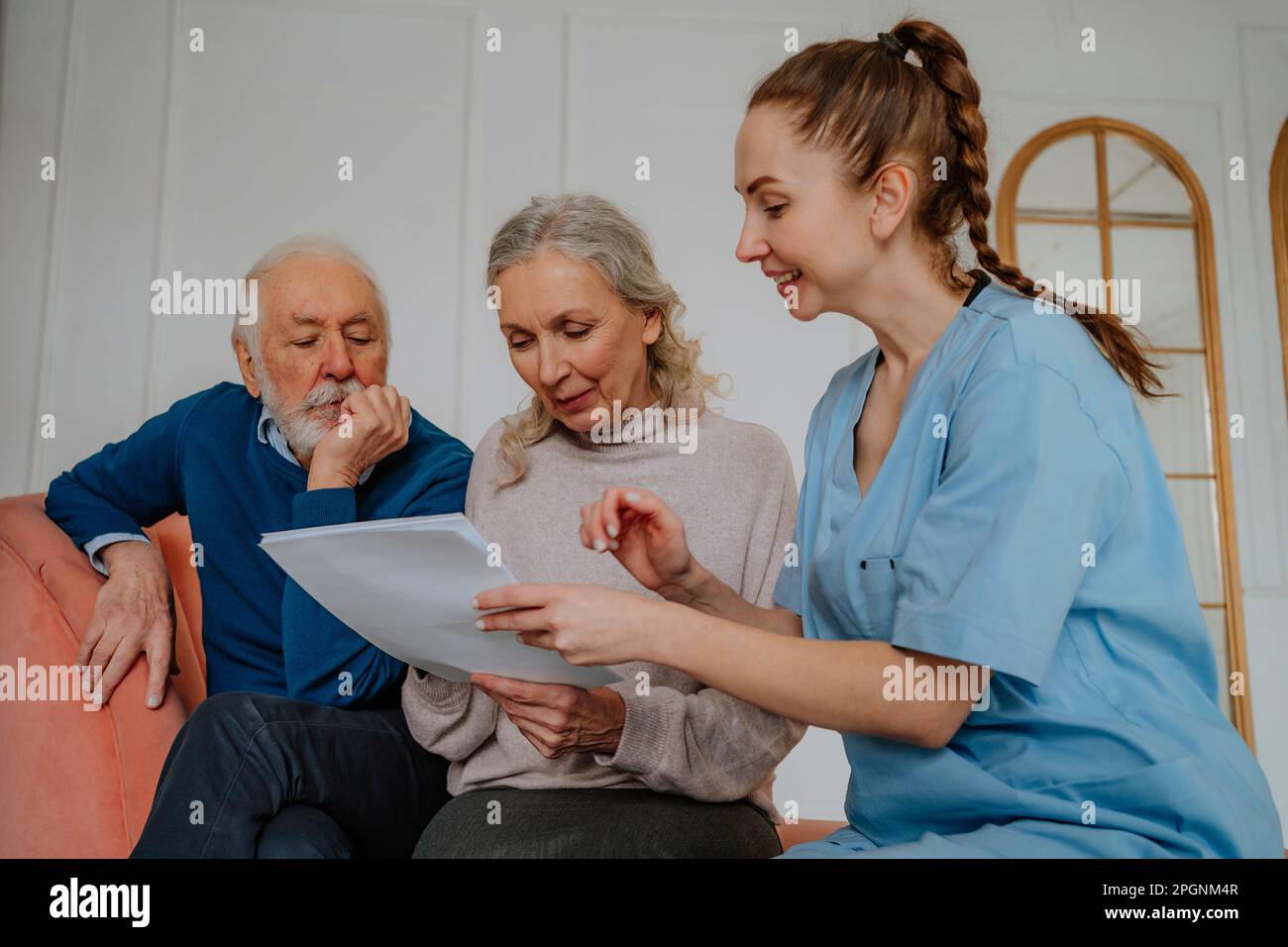 Pazienti anziani che leggono referti medici da parte di un infermiere a casa Foto Stock