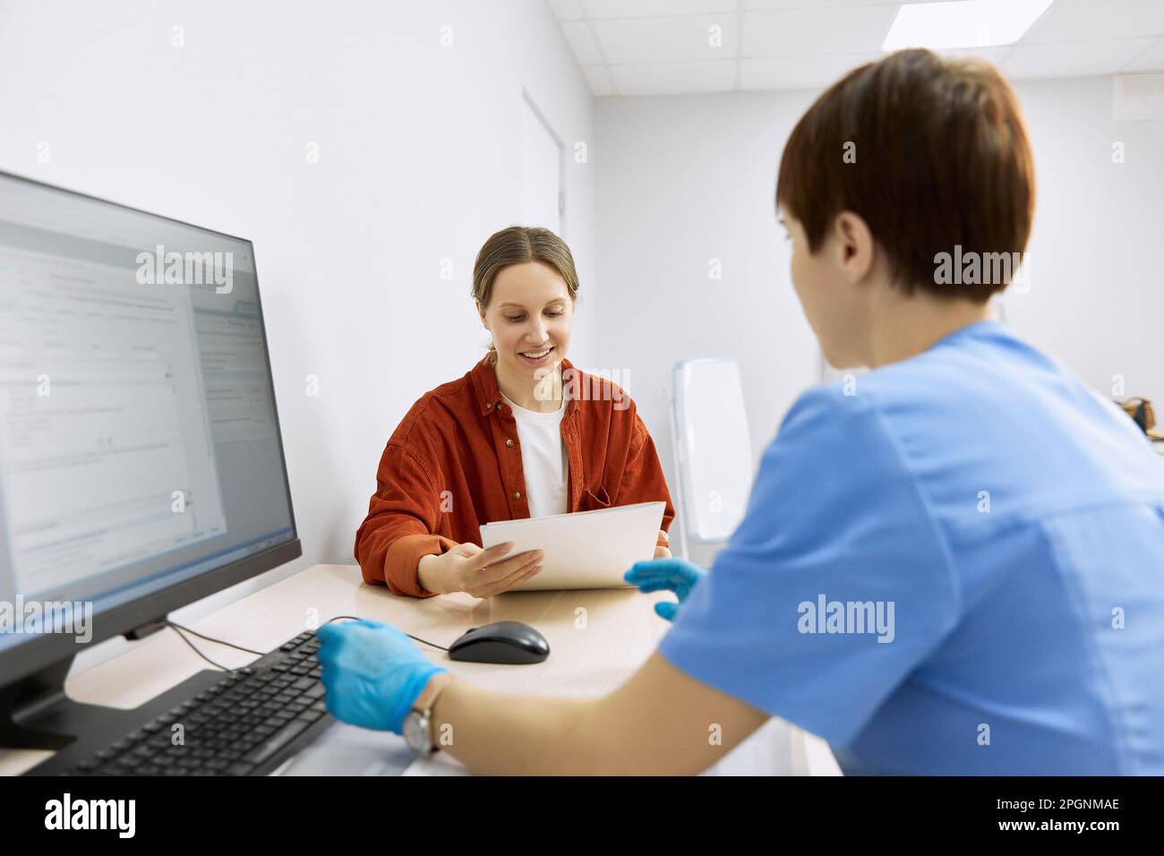 Oftalmologo che discute con il paziente che legge il rapporto in clinica Foto Stock