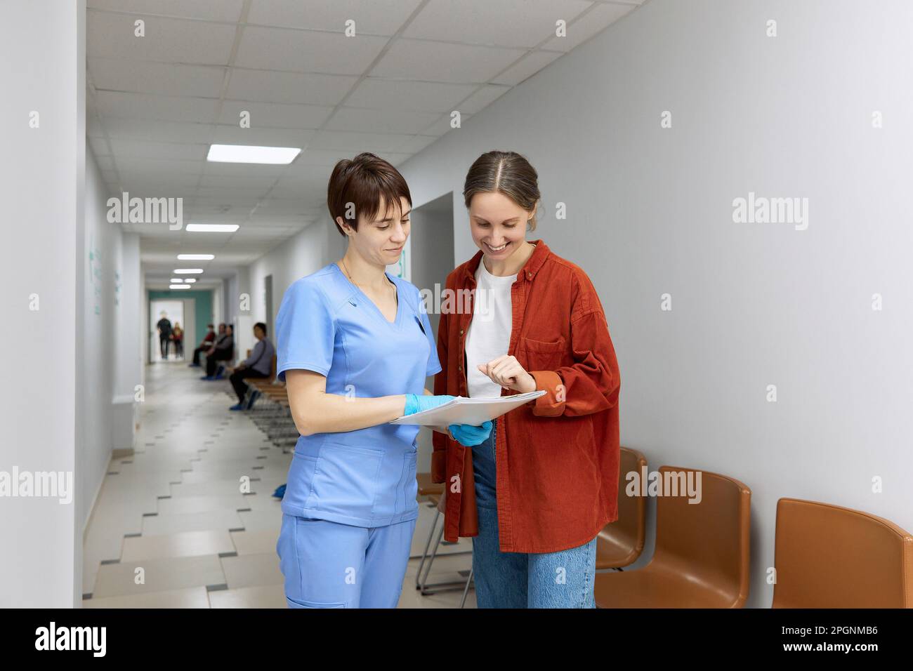 Medico e paziente che rivedono i risultati dei test in piedi in corridoio presso l'ospedale Foto Stock