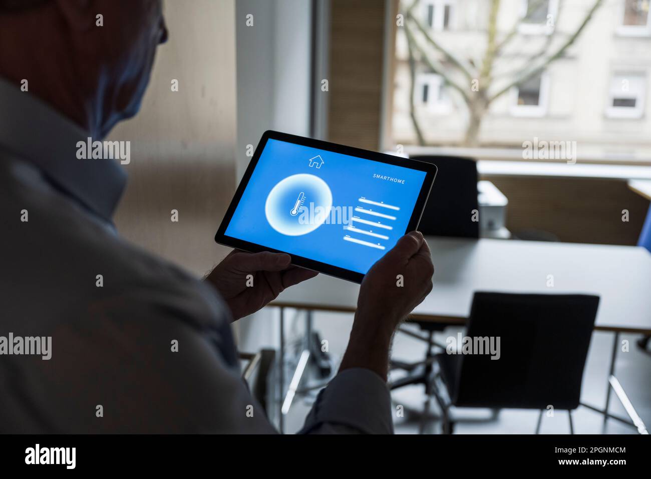 Uomo d'affari con tablet PC che mostra la visualizzazione dell'app di automazione domestica in ufficio Foto Stock