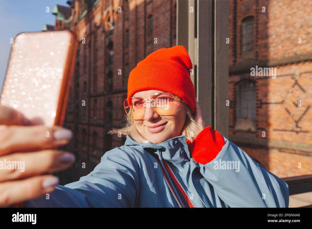 Donna in abiti caldi che prende selfie attraverso lo smartphone Foto Stock
