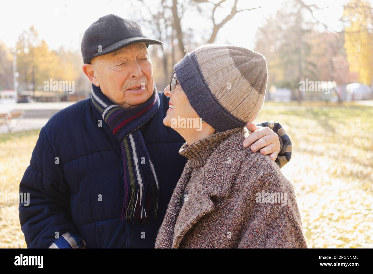 Uomo anziano con braccio intorno alla donna al parco autunnale Foto Stock