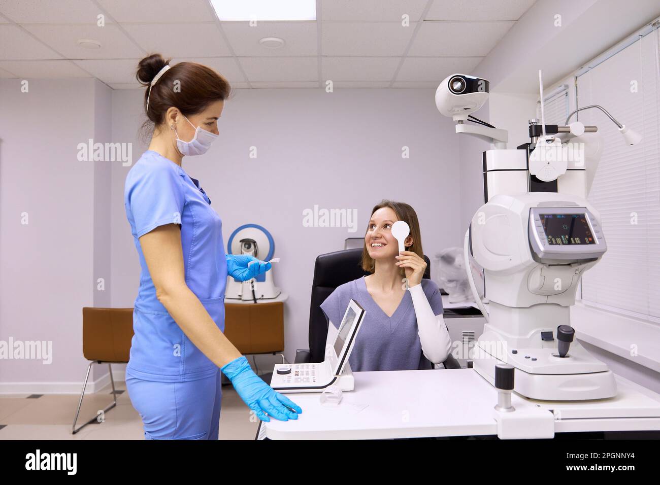 Paziente sorridente che parla con oftalmologo in clinica medica Foto Stock