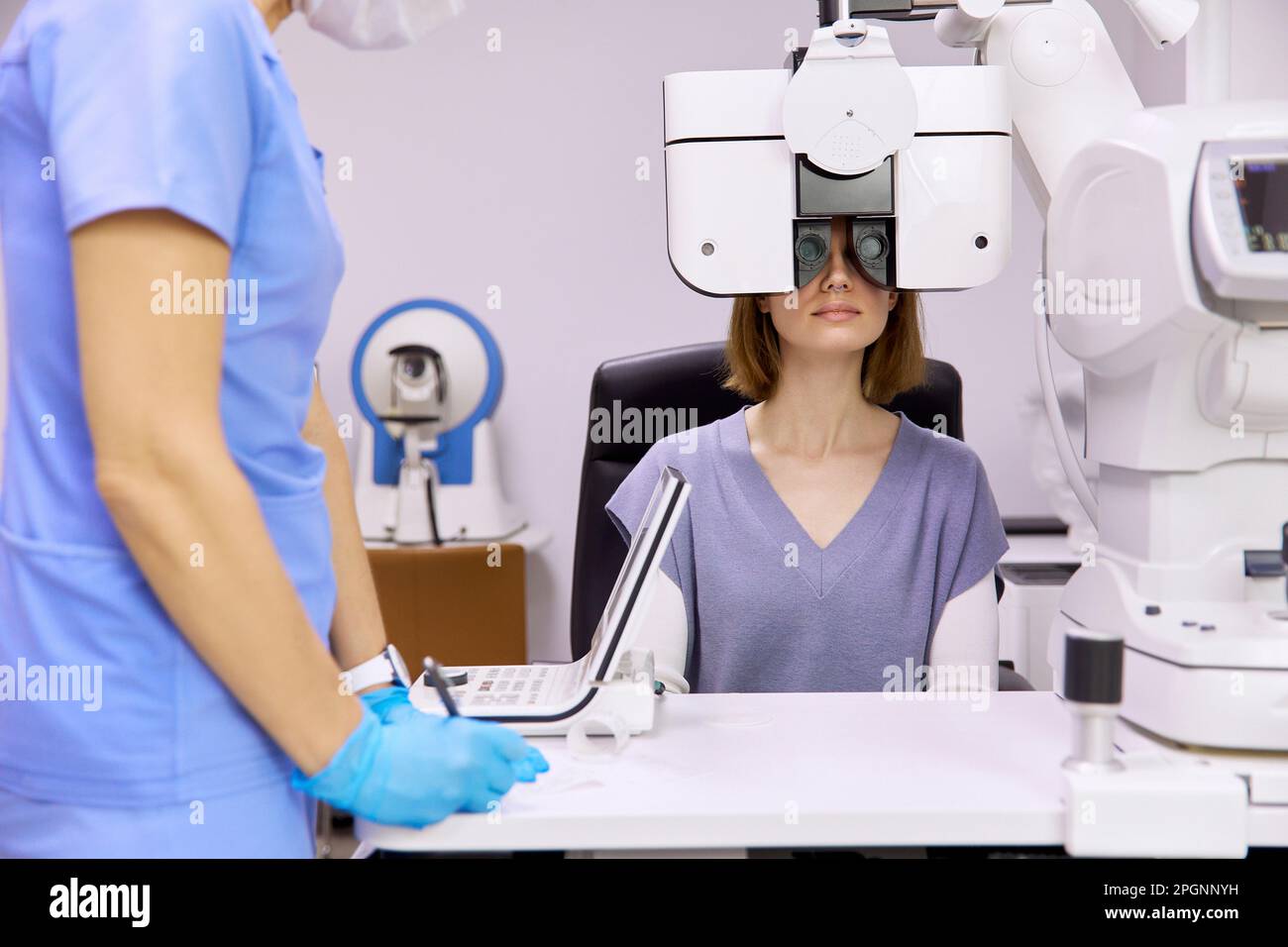 Il medico con il paziente che fa il controllo della vista attraverso il foropter alla clinica Foto Stock