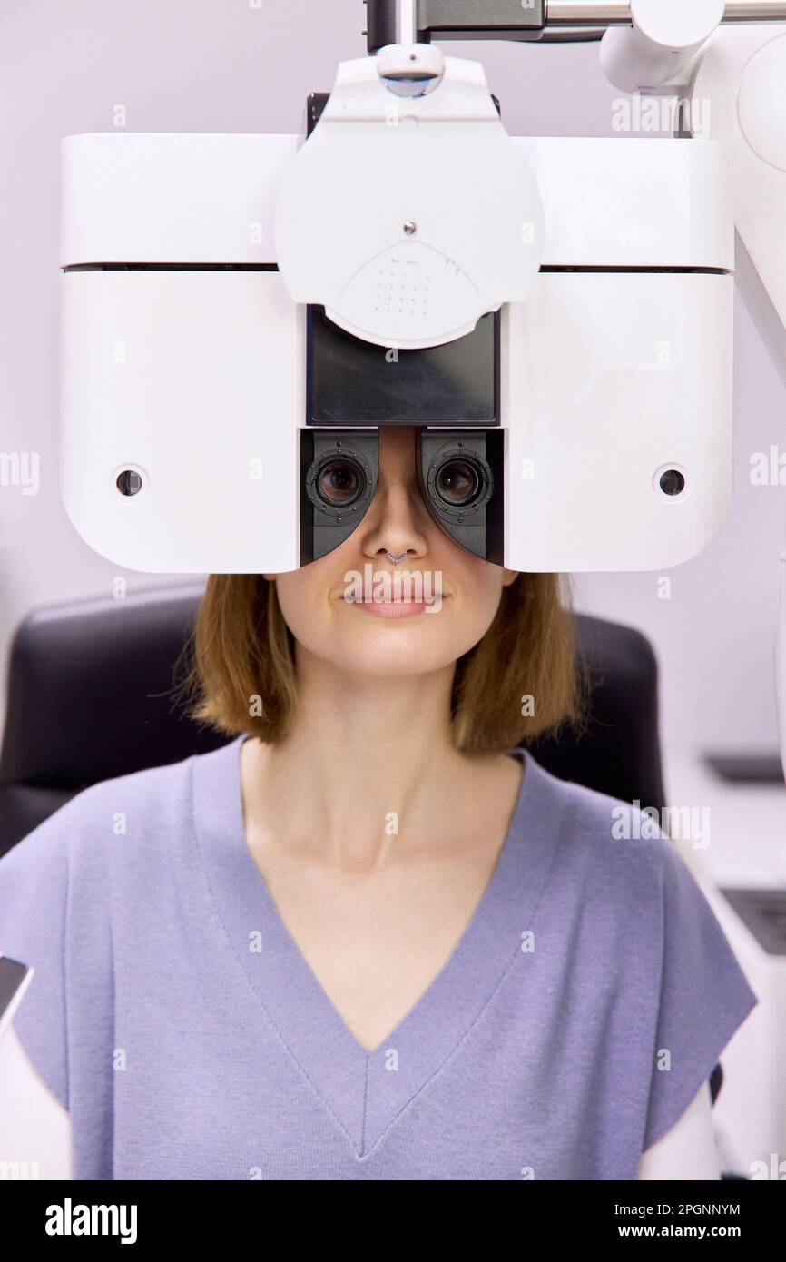 Paziente che esegue il controllo visivo attraverso il foropter presso la clinica Foto Stock