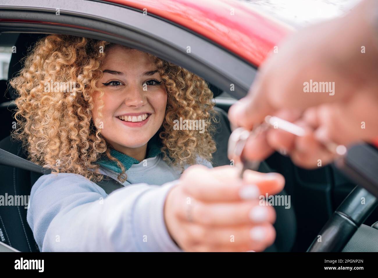 Donna felice che dà le chiavi dell'auto al cameriere personale Foto Stock