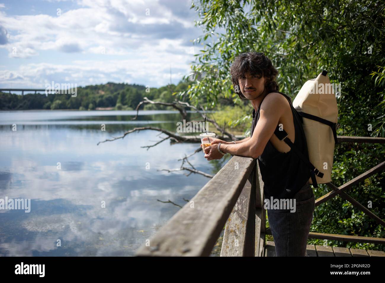 Giovane uomo che indossa lo zaino in piedi sulla ringhiera Foto Stock