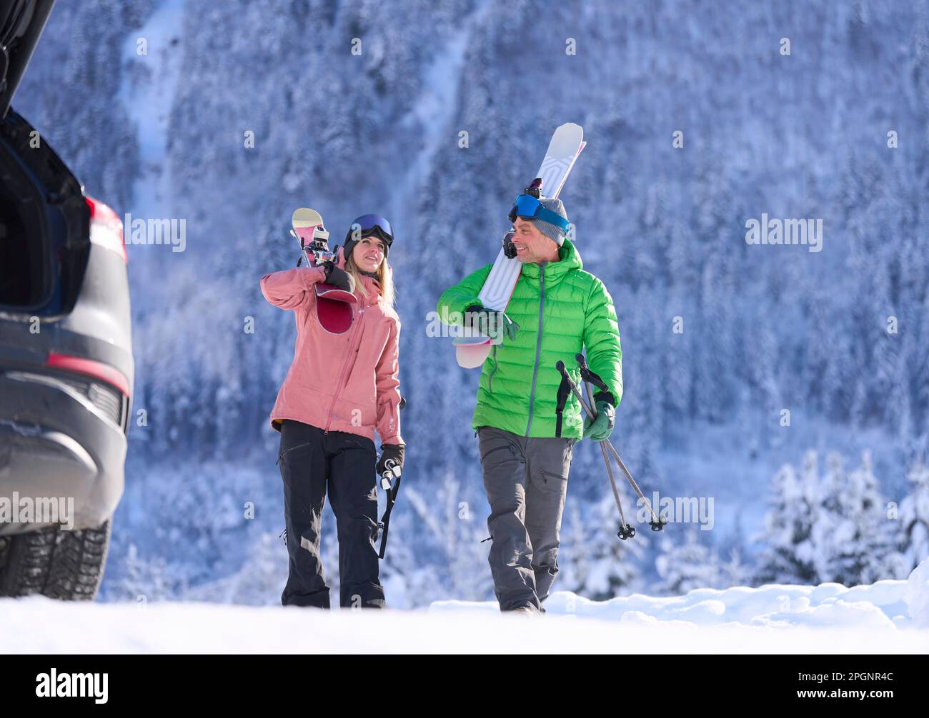 Uomo e donna che camminano con sci e pali davanti alla montagna Foto Stock