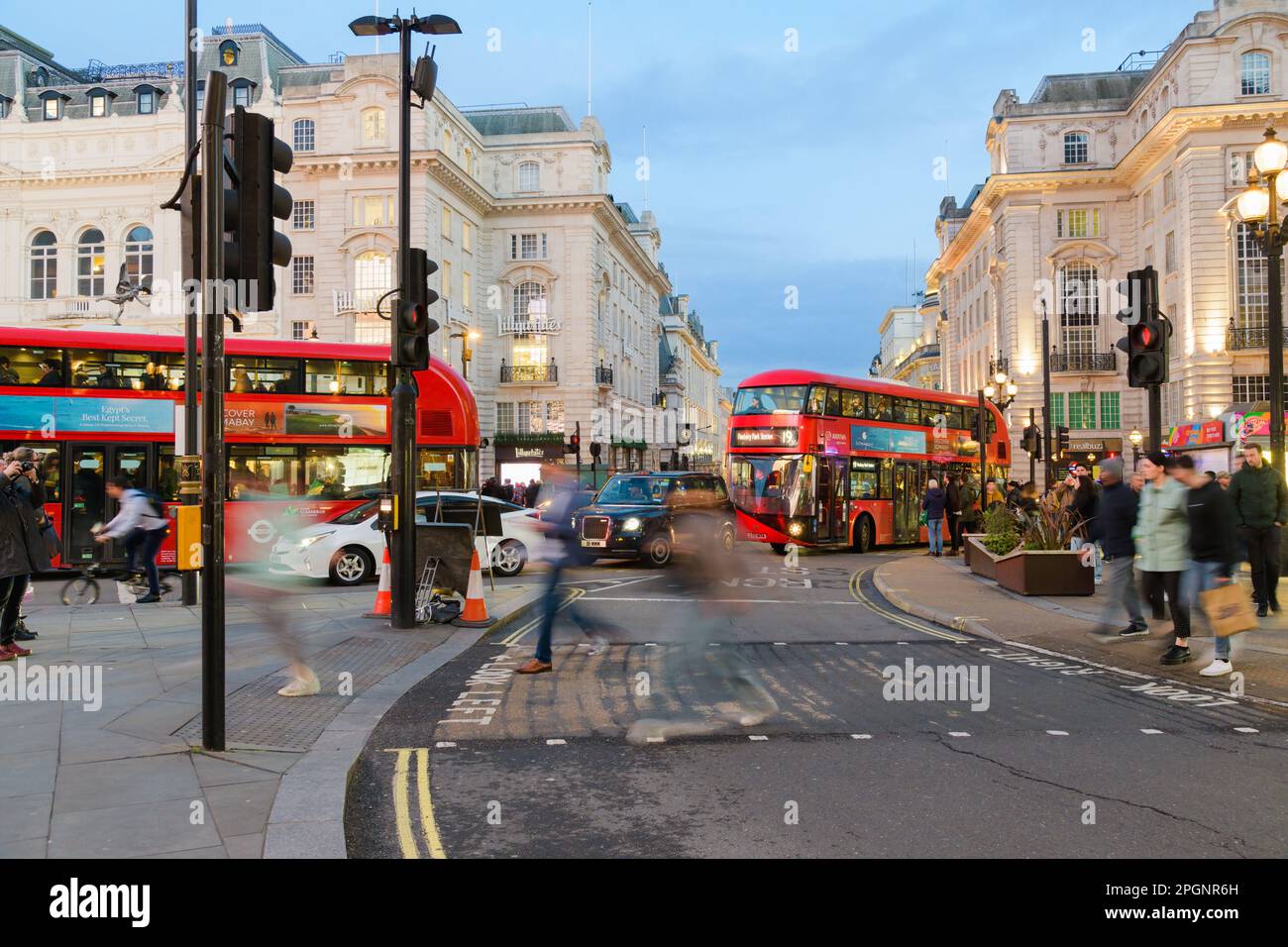 Londra, Regno Unito - Marzo 17 2023; il traffico delle persone e gli autobus di Londra passano attraverso Piccadilly Circus al crepuscolo Foto Stock