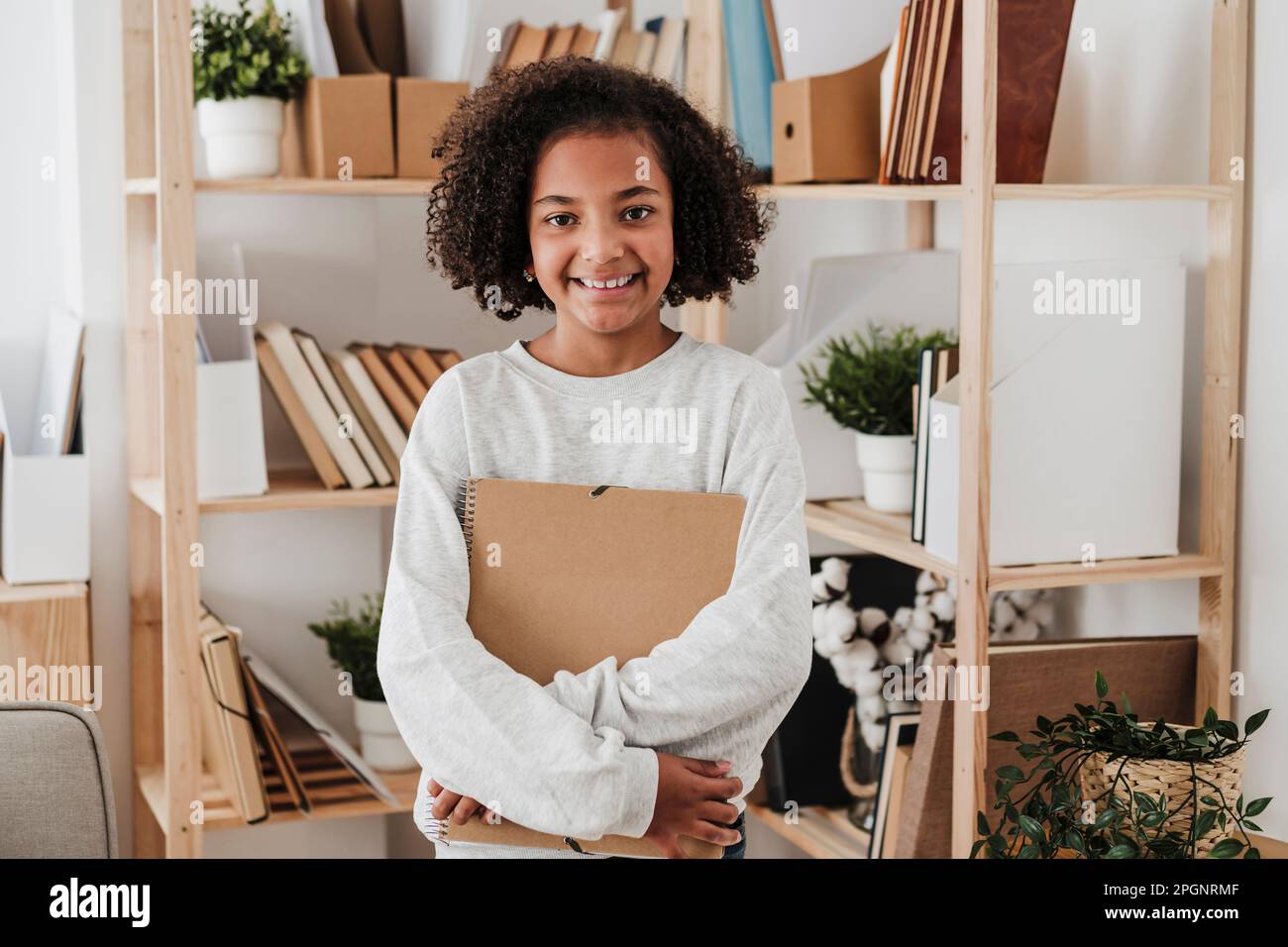 Ragazza sorridente che tiene a casa un notebook a spirale Foto Stock