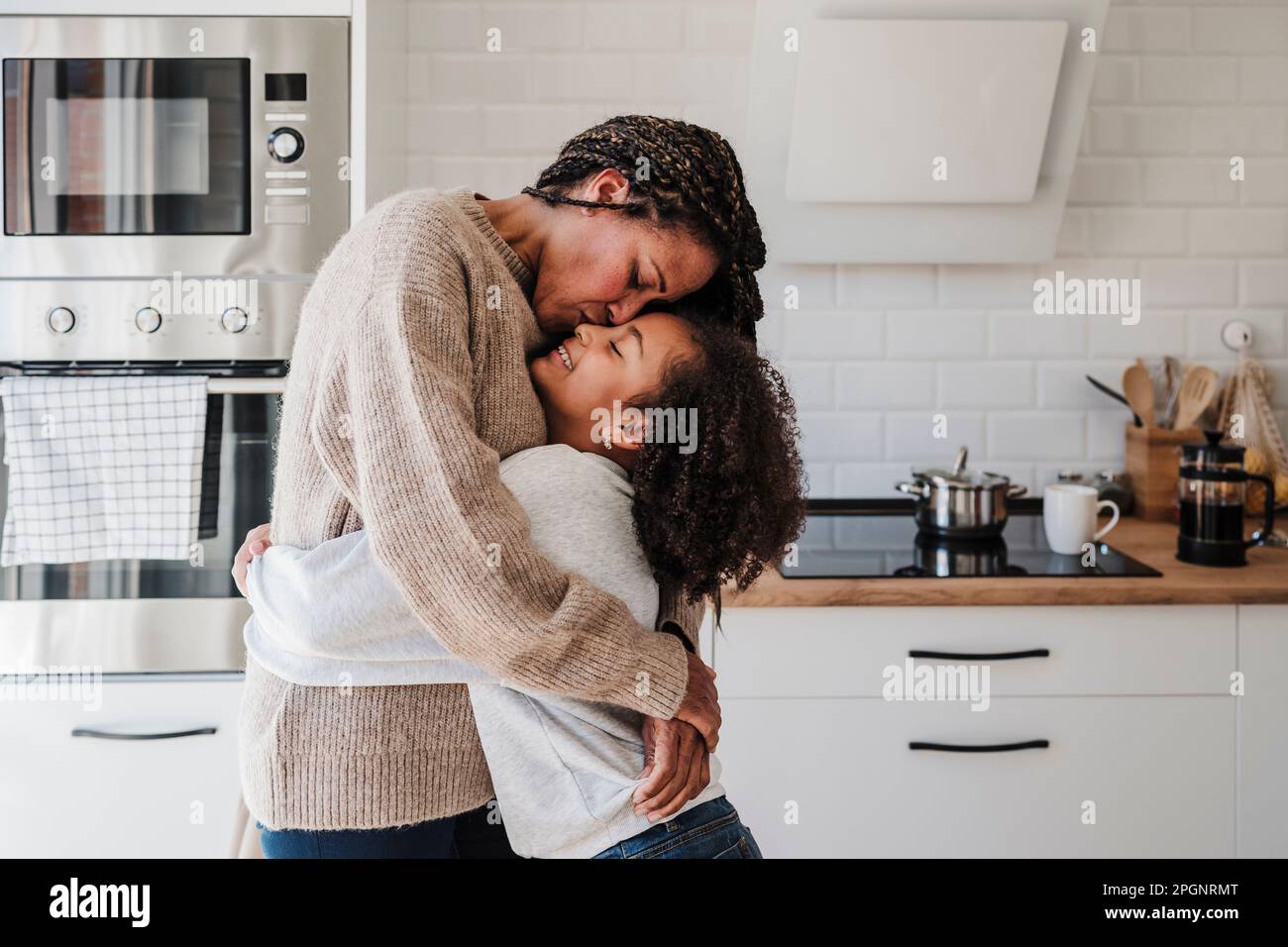 Madre bacia figlia in cucina a casa Foto Stock