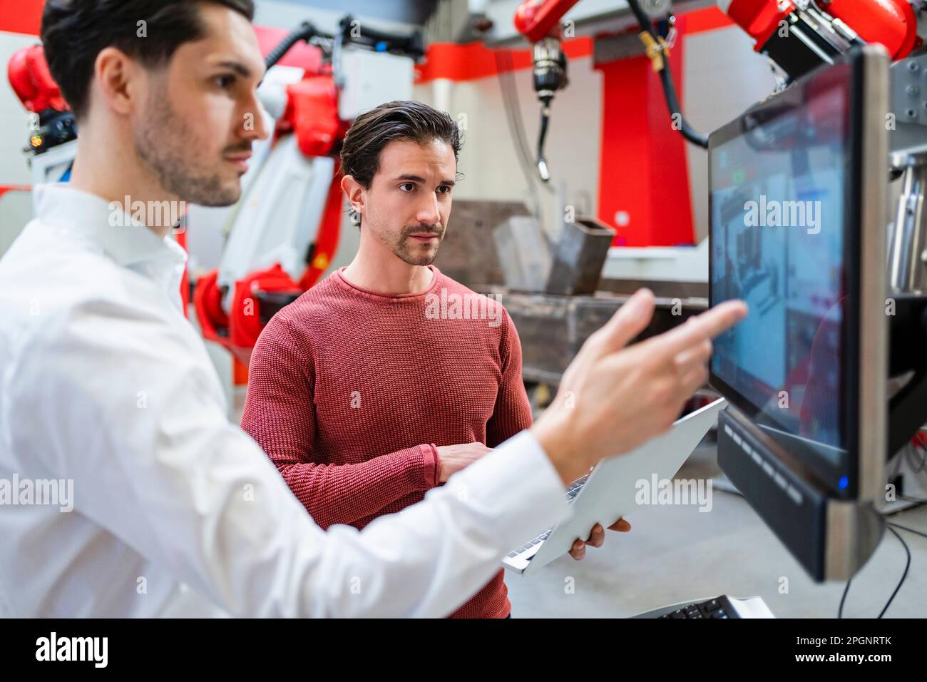Ingegneri che lavorano insieme sullo schermo del computer presso la fabbrica di robot Foto Stock
