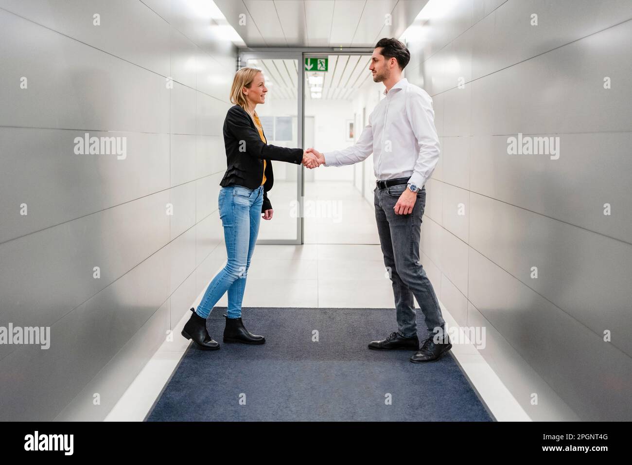 Colleghi che fanno la stretta di mano in corridoio Foto Stock