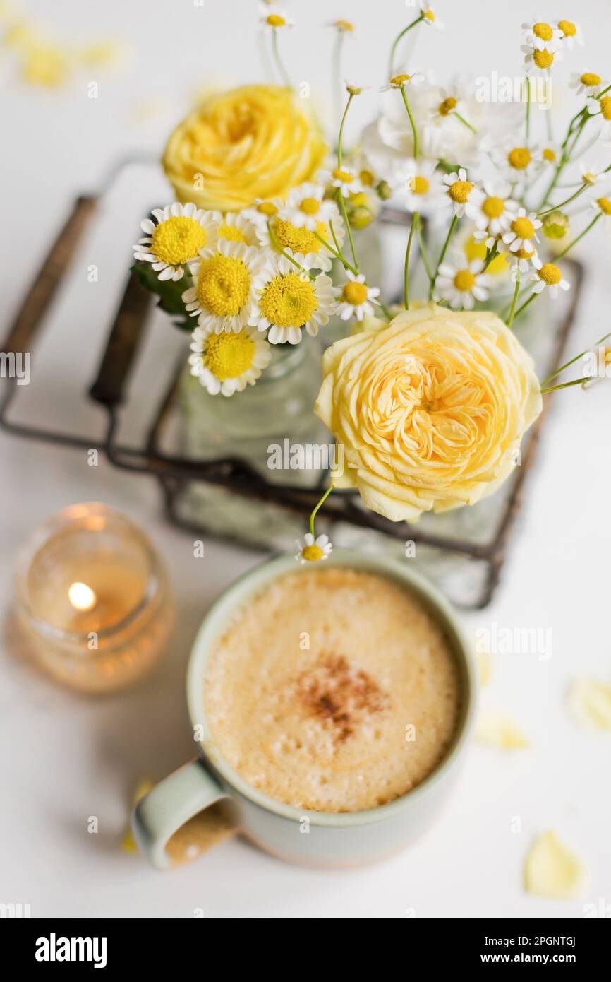 Tazza di caffè con fiori gialli e bianchi sul tavolo Foto Stock