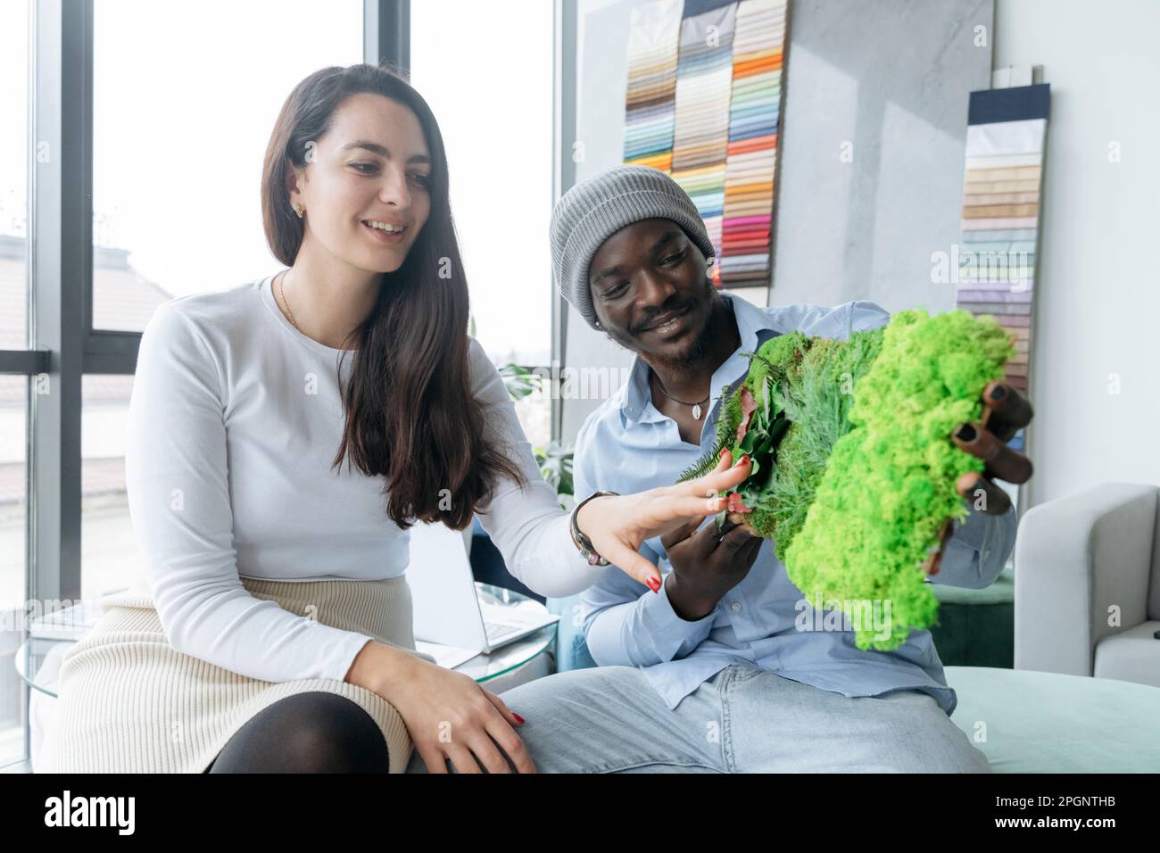 Architetti sorridenti che esaminano un campione di parete verde in ufficio Foto Stock