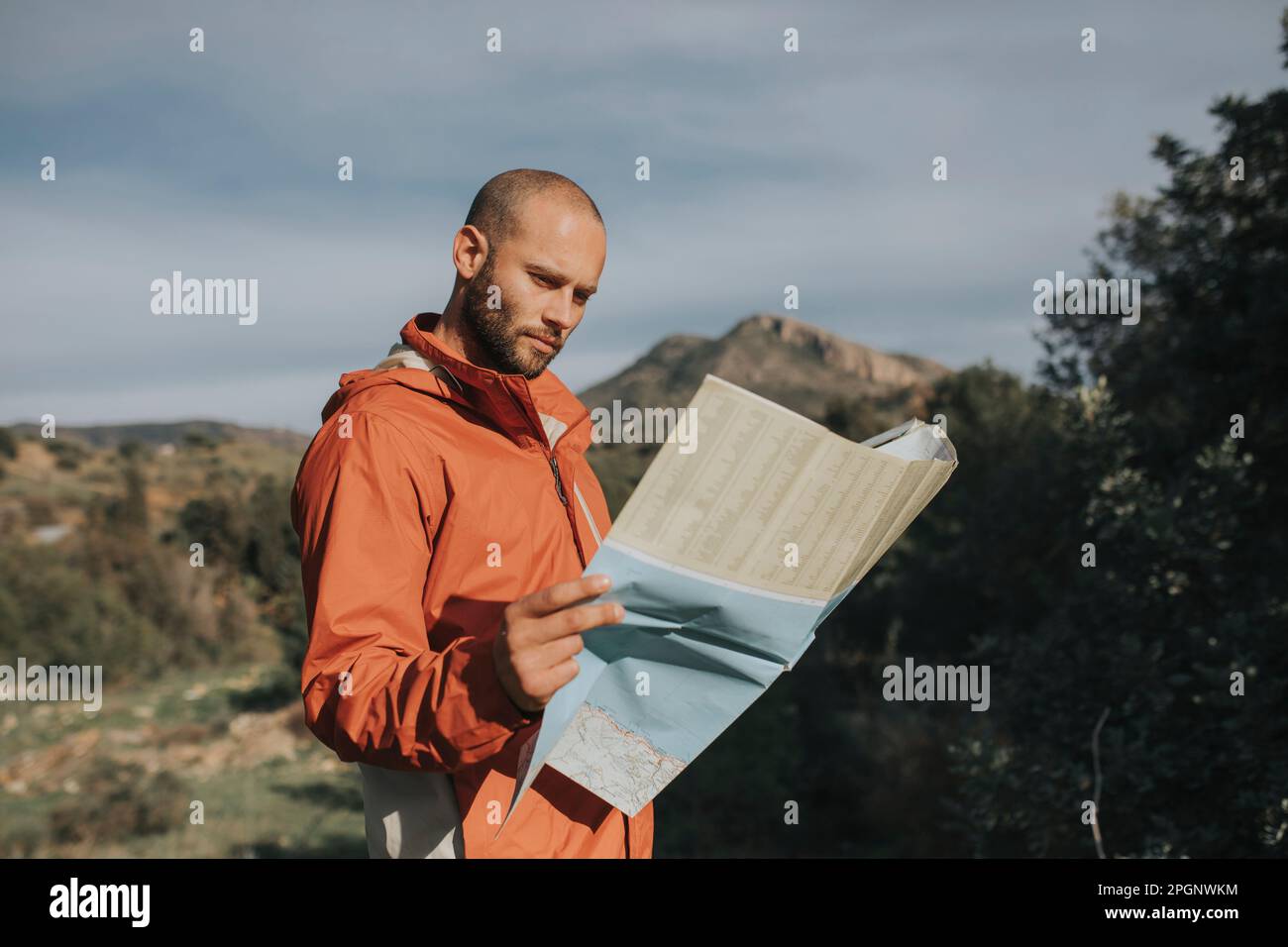 Uomo sorridente che legge la mappa in piedi nella natura Foto Stock