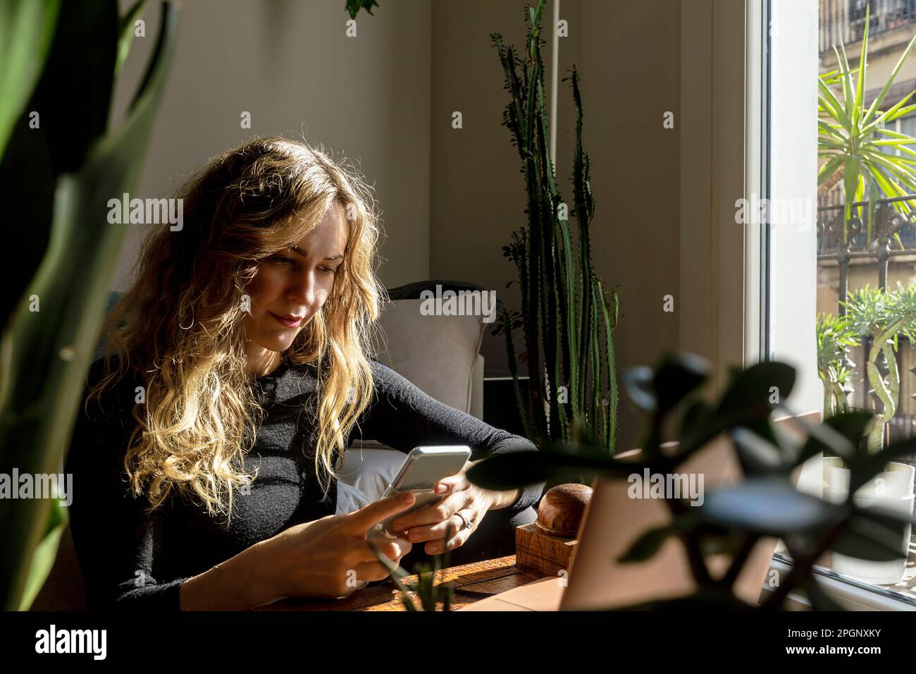 Donna che usa lo smartphone nel soggiorno di casa Foto Stock