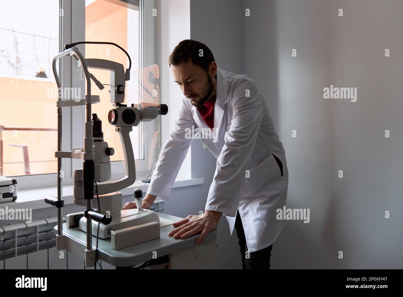 Il medico che esamina la macchina dello scanner dell'occhio alla clinica Foto Stock