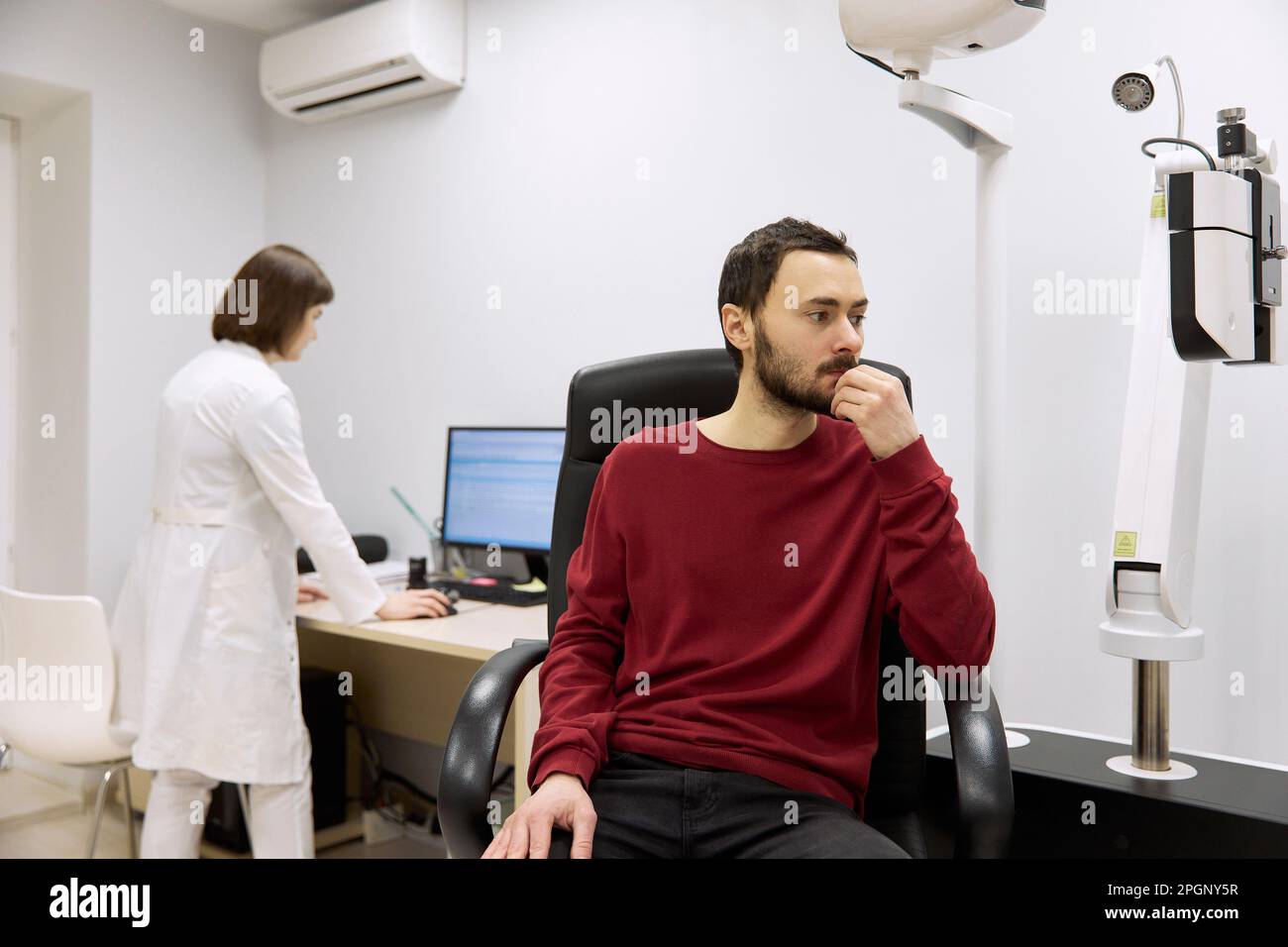Paziente con mano sul mento in attesa in clinica Foto Stock