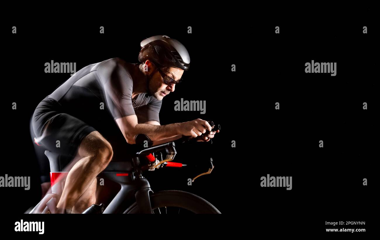 Ciclista seduta sul turbo trainer su sfondo nero Foto Stock