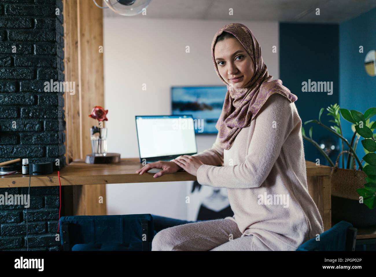 Freelance che indossa hijab seduto al tavolo in ufficio a casa Foto Stock