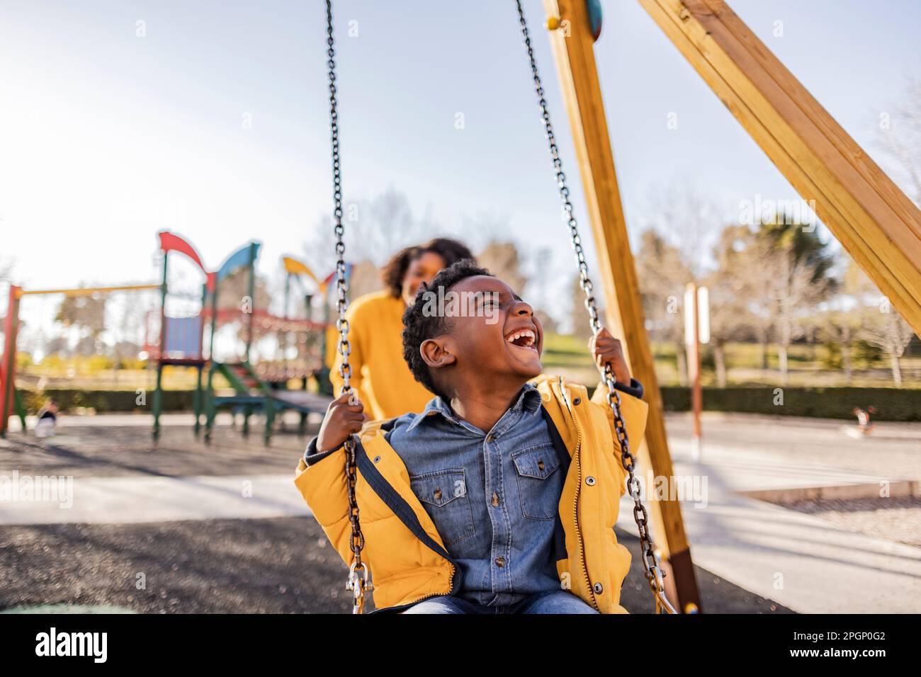 Madre figlio di spinta su swing sul parco giochi Foto Stock