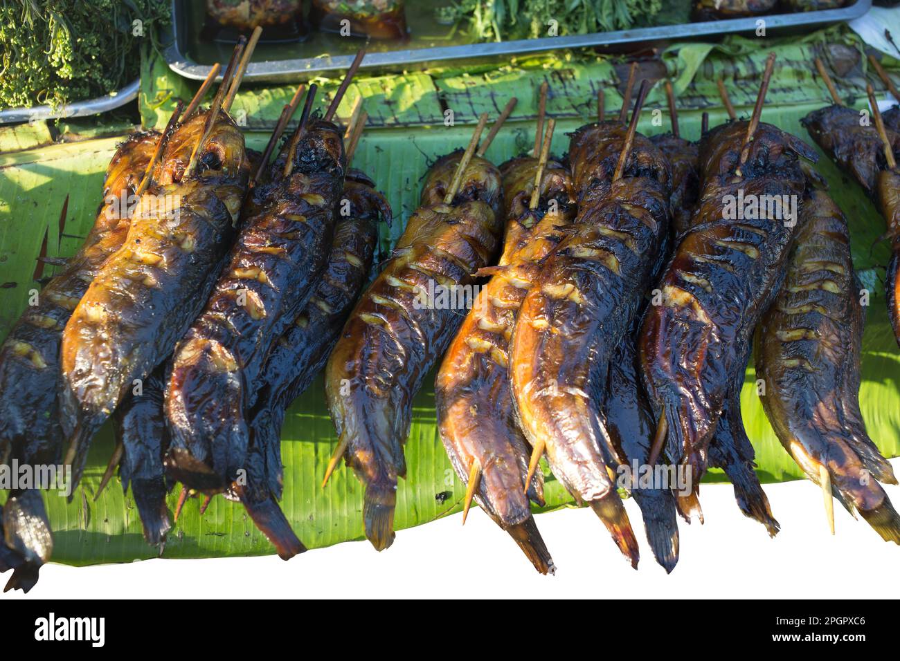Fustellato di pesce gatto alla griglia sulla foglia di banana su bianco isolato. Foto Stock