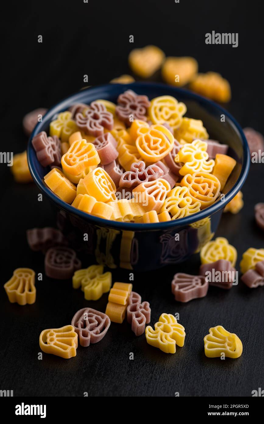 Pasta di varie forme spaventose. Pasta di Halloween cruda in un recipiente. Foto Stock