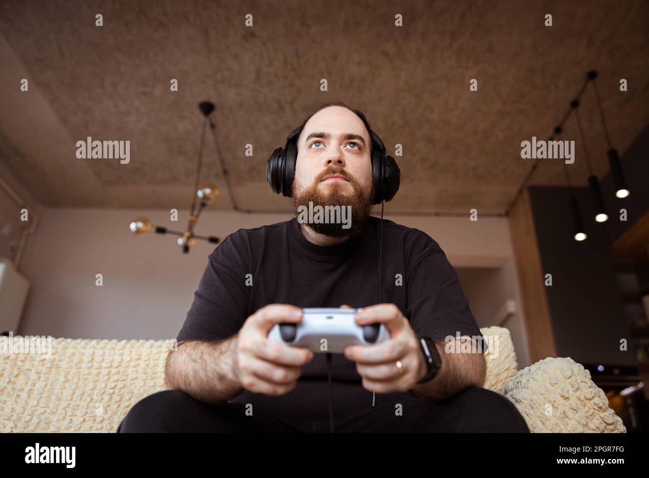 Stile di vita di un giovane giocatore maschio che gioca su console con cuffie e auricolari tenendo l'ontroller gioco nelle sue mani. Foto Stock