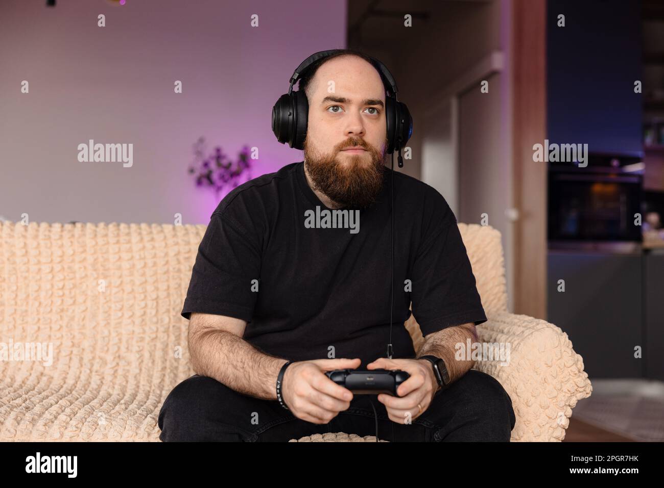 Giocatore maschio che gioca ai videogiochi con il controller nelle sue mani. e le sue cuffie. Espressione del volto di un giocatore. Foto Stock