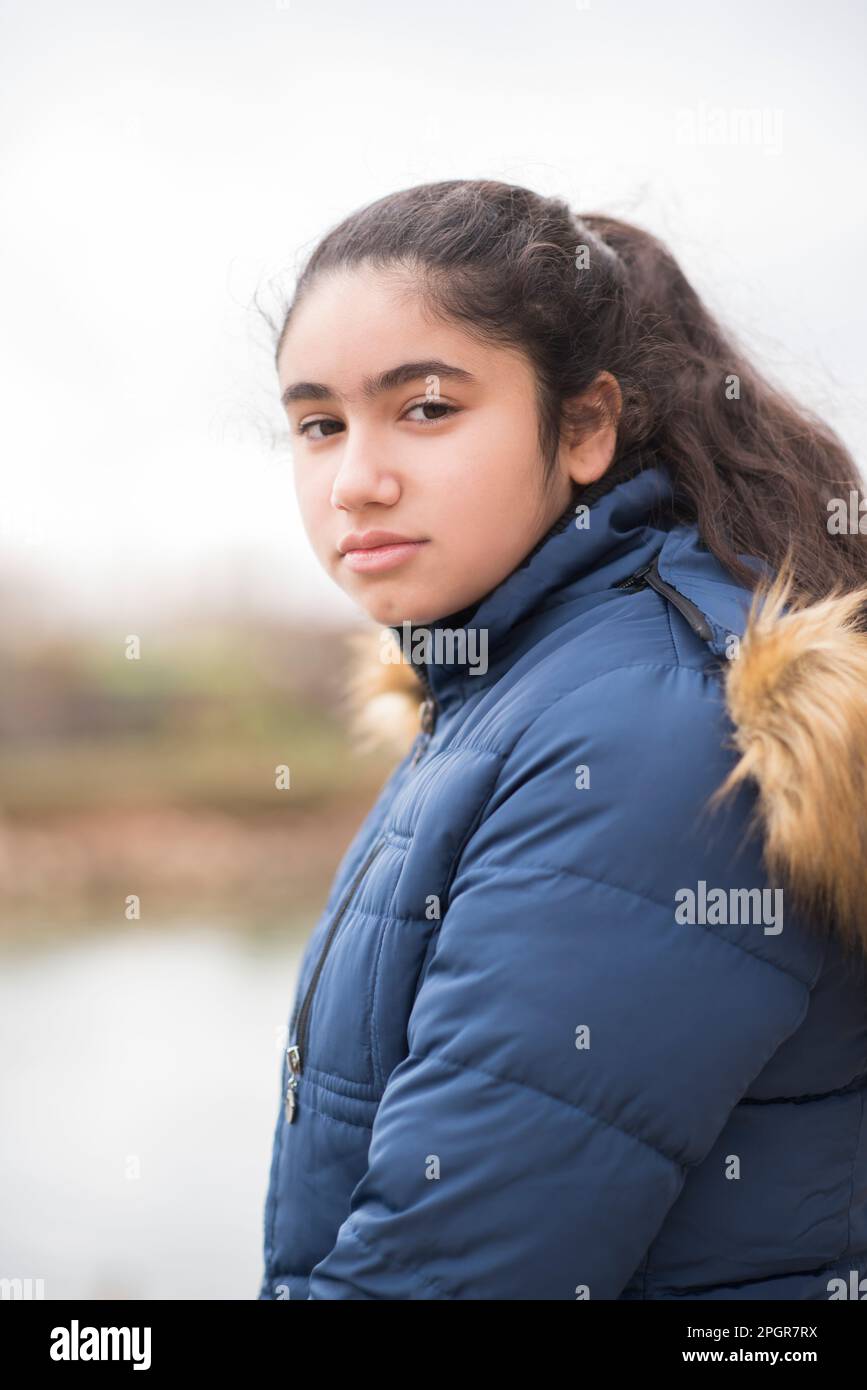 Bella ragazza adolescente in giacca invernale guardando la fotocamera all'aperto Foto Stock