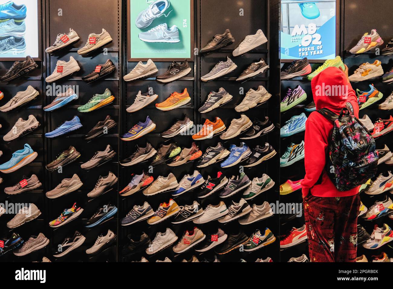 Le grandi vetrine del negozio mostrano una gamma di scarpe e abbigliamento sportivo, con i clienti che acquistano scarpe. Foot Locker, il rivenditore di calzature con sede negli Stati Uniti, sta subendo una trasformazione in Asia in quanto intende semplificare il proprio modello di business e concentrarsi sulle aree principali e sui banner. Come parte di ciò, Foot Locker chiuderà sia i suoi negozi di e-commerce che i negozi di Hong Kong e Macau, convertendo tutti i suoi attuali negozi di proprietà e self-operated e l'e-commerce di Singapore e Malesia in un modello di licenza. I risultati del quarto trimestre 2022 di Foot Locker hanno rivelato che l'azienda sta prendendo una serie Foto Stock