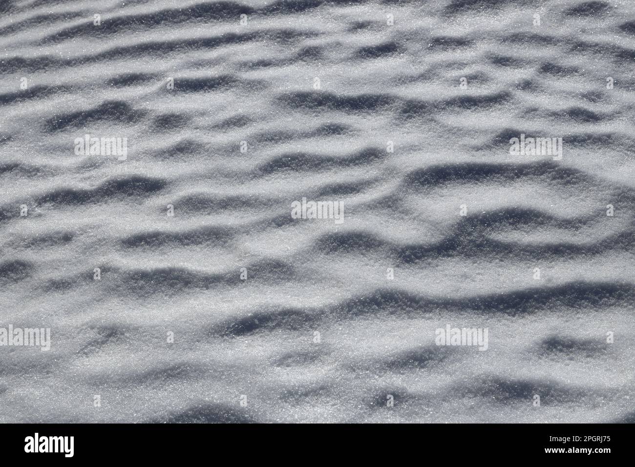 Neve ondulata illuminata dal sole del mattino in primo piano primaverile Foto Stock