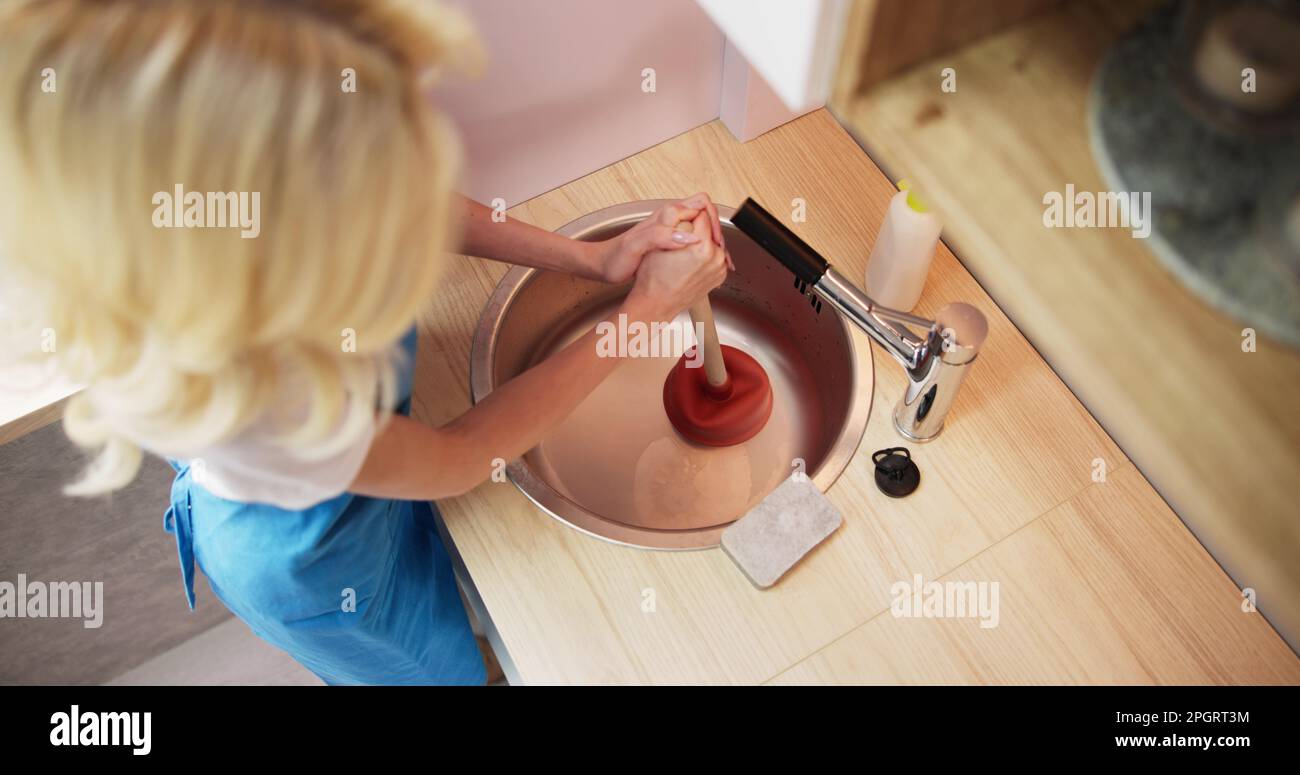 Pulizia dell'ostruzione dello scarico bloccata nel lavandino da cucina con il pistone Foto Stock