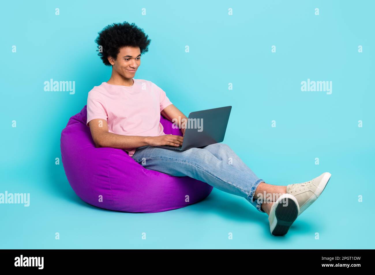 Immagine a grandezza naturale di un giovane studente uomo tempo libero chattando con gli amici penna messaggero remoto dormitorio pouf isolato su sfondo color acquamarina Foto Stock