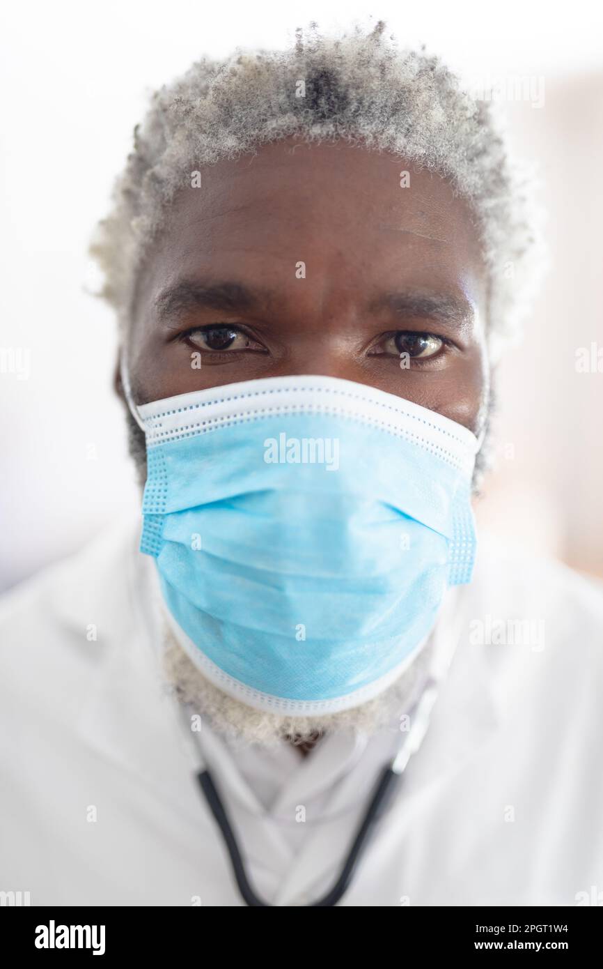 afroamericano medico senior maschile guardando la fotocamera indossare maschera facciale. medico al lavoro durante la pandemia di coronavirus covid 19. Foto Stock