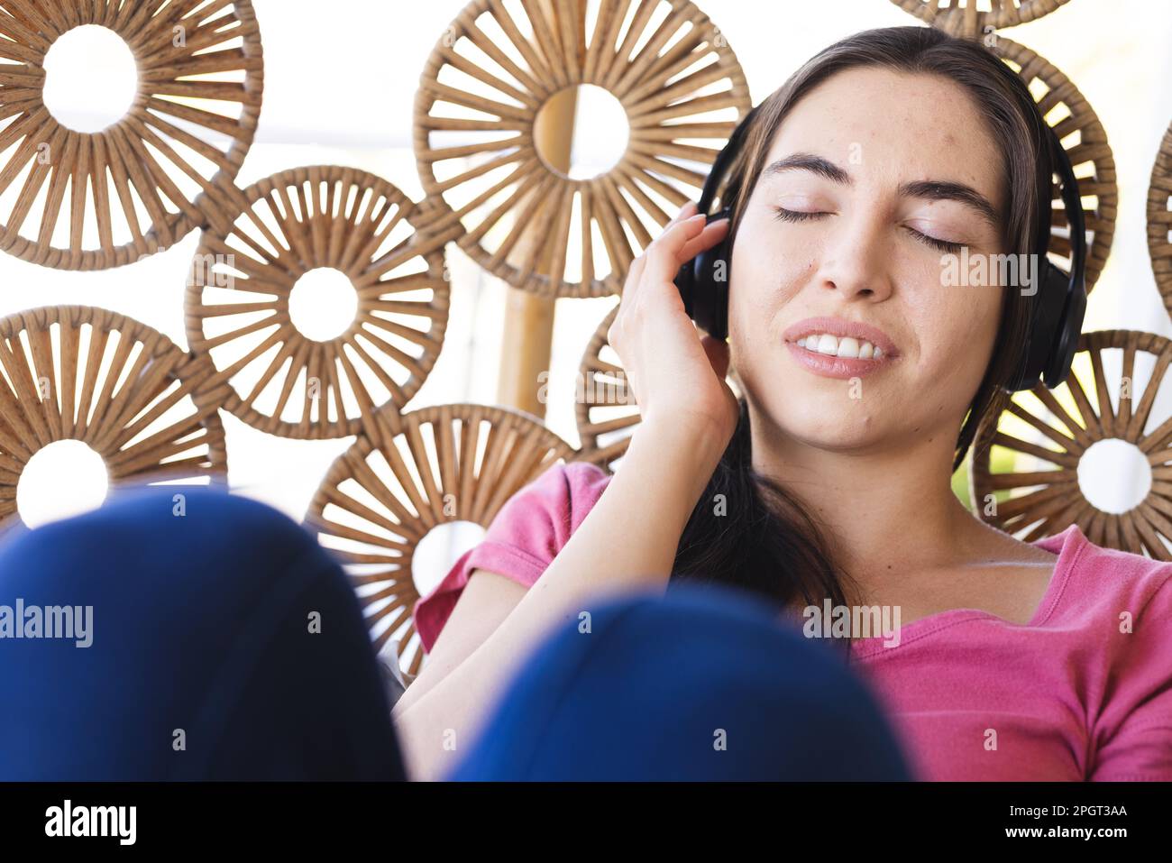 Primo piano di una giovane donna caucasica con gli occhi chiusi ascoltando musica sulle cuffie in oscillazione. Inalterato, tecnologia, stile di vita, relax e casa conc Foto Stock