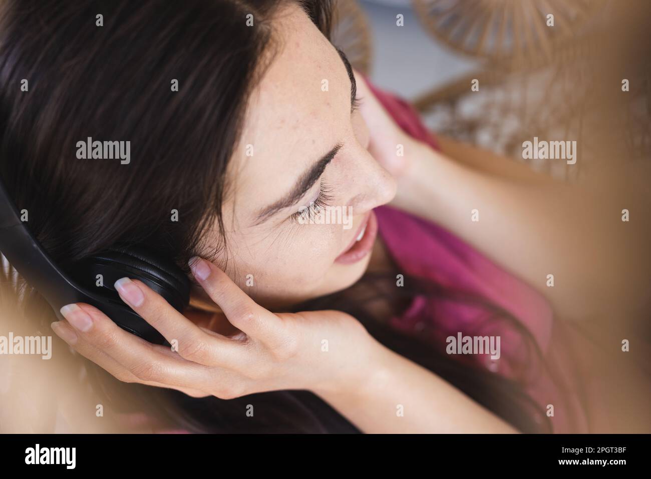 Primo piano ad alto angolo di una bella giovane donna caucasica che ascolta la musica con le cuffie a casa. Inalterato, tecnologia, stile di vita Foto Stock