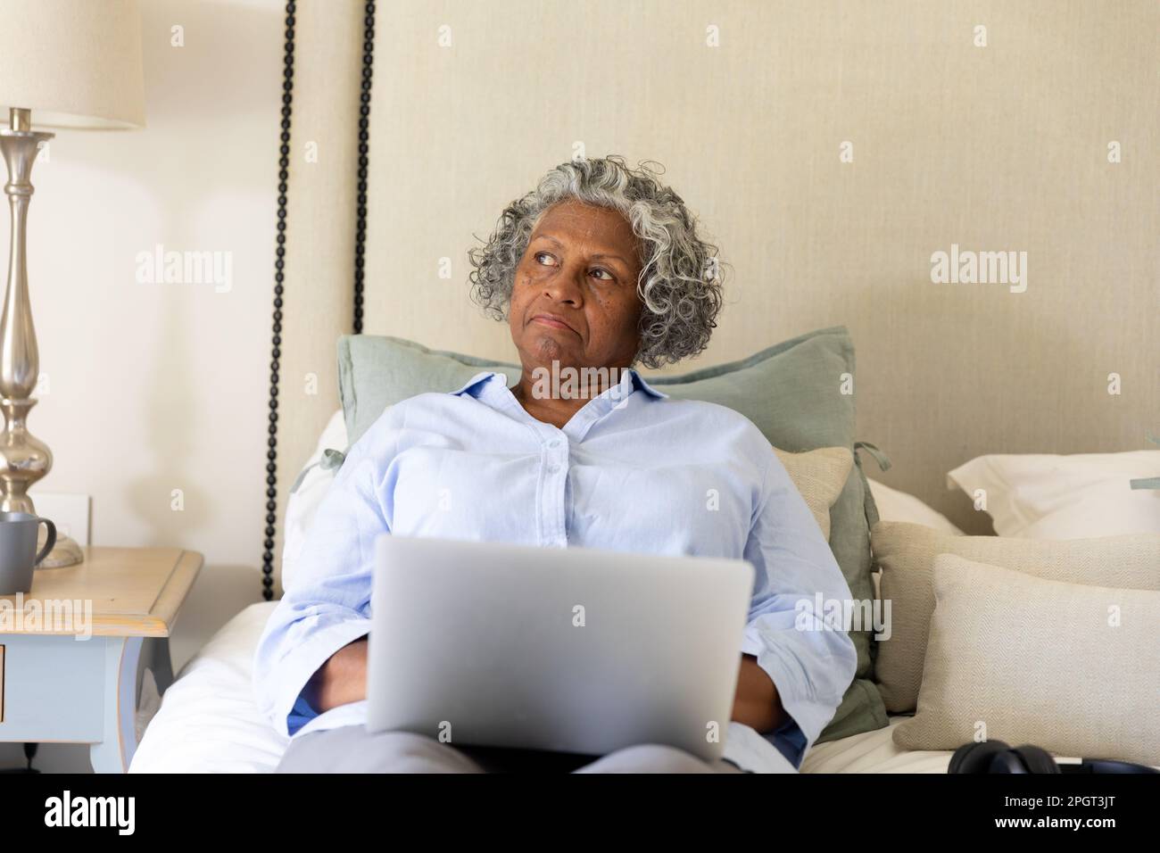 afroamericana senior businesswoman contemplare mentre si lavora su un computer portatile a letto, copia spazio. Inalterato, professionale, lavoro da casa, pensivo e. Foto Stock