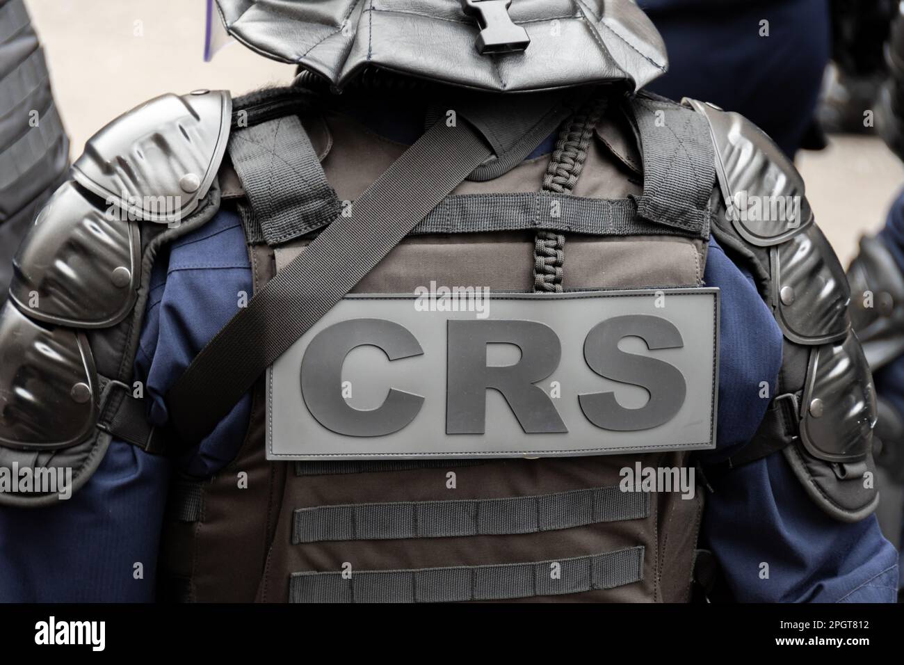 Primo piano 'CRS' (polizia antisommossa) marcatura scritta sul retro di un giubbotto tattico indossato da un ufficiale di polizia in una strada di Parigi, Francia Foto Stock