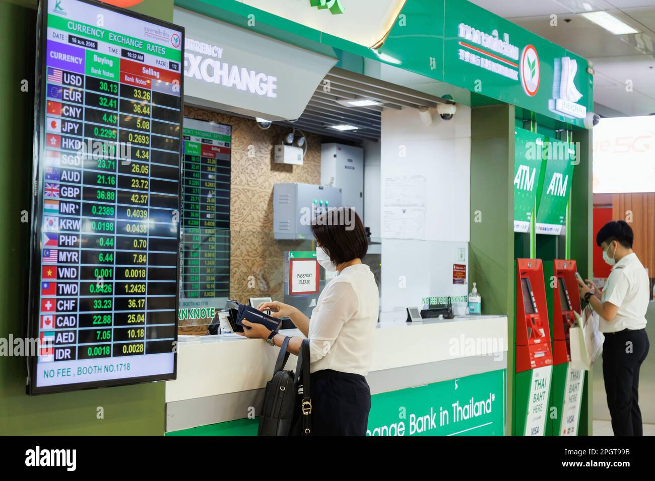 Bangkok, Thailandia - 1 febbraio 2023 : viaggiatore d'affari asiatico in banca sportello di cambio di denaro presso l'aeroporto suvarnabhumi con tasso di cambio di valuta disp Foto Stock