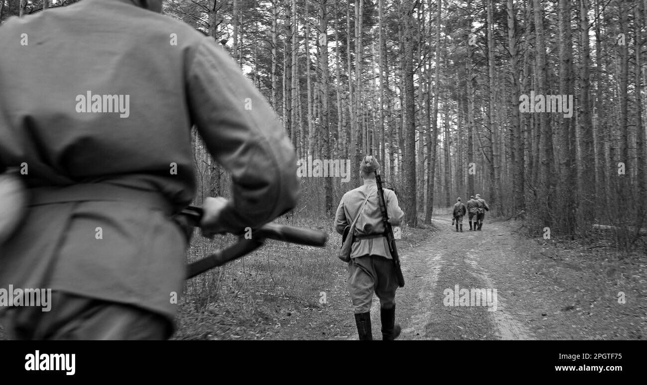 Re-enactors vestito come soldati russi sovietici dell'esercito rosso della seconda guerra mondiale marciando camminando lungo Forest Lane Road in primavera Autumn Day. Gruppo Foto Stock