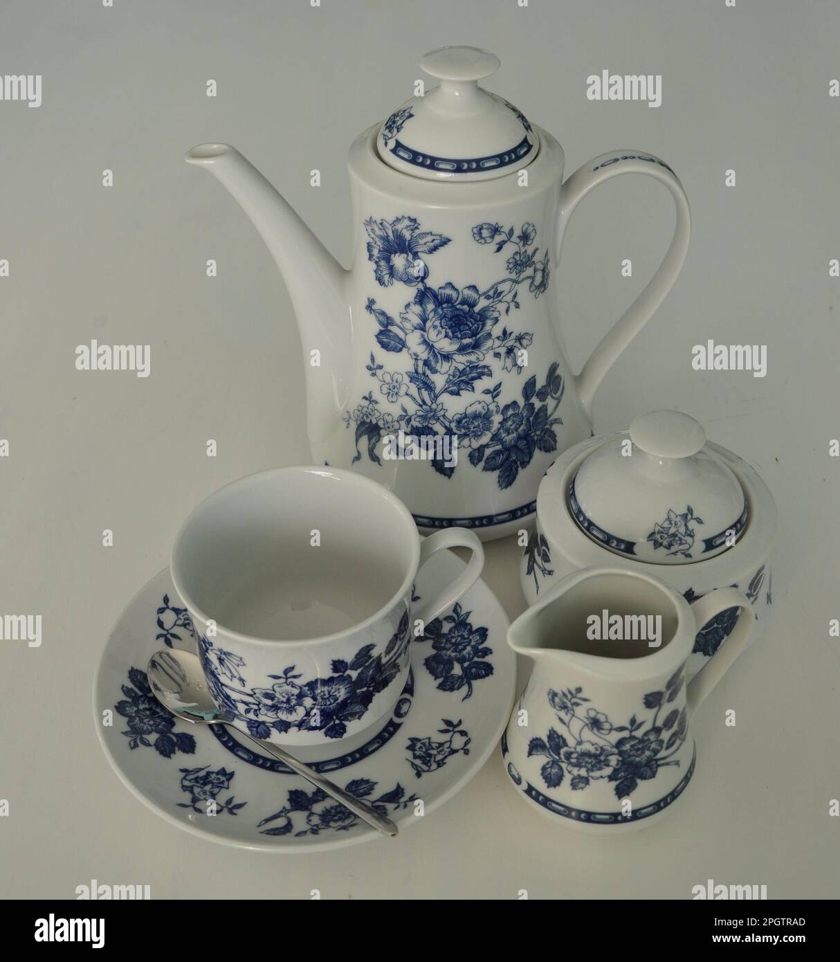 Set completo di caffè, latte e zucchero su sfondo bianco. Splendido servizio di cena bianca con decorazioni blu isolate su un tavolo bianco. Latte Foto Stock