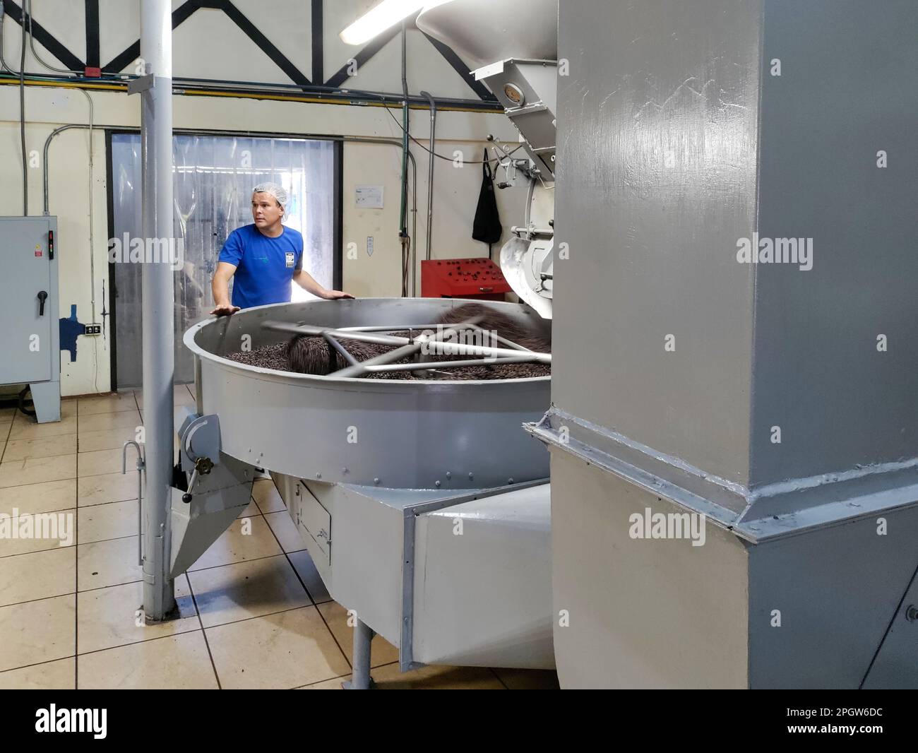 Naranjo, Costa Rica - Un operaio sovrintende alla torrefazione dei chicchi di caffè presso la fattoria e l'impianto di lavorazione del caffè Espiritu Santo. Foto Stock