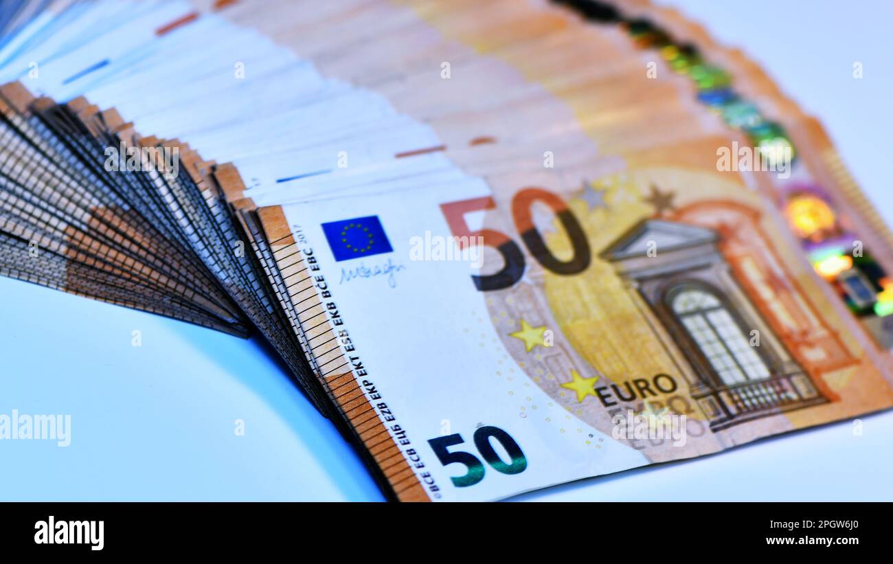 Concetto di molti euro: Un mucchio di banconote arrotolate da 50 euro giacenti su uno sfondo bianco, pila di banconote da 50 euro background commerciale Foto Stock