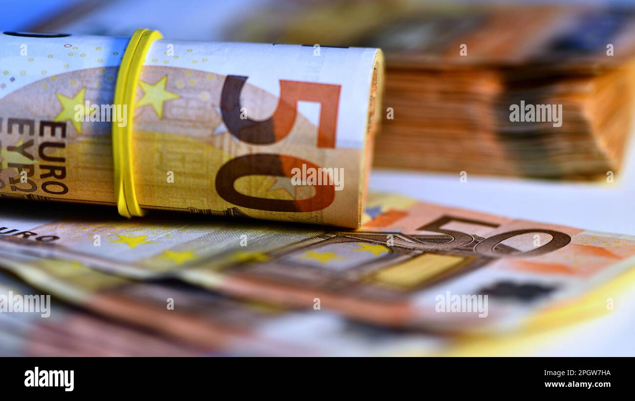 Concetto di molti euro: Un mucchio di banconote arrotolate da 50 euro giacenti su uno sfondo bianco, pila di banconote da 50 euro background commerciale Foto Stock